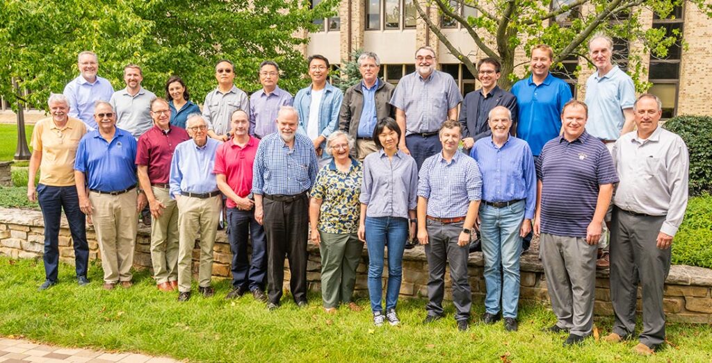 Group of faculty members from the Department of Electrical Engineering posing outdoors on a lawn in front of Fitzpatrick Hall of Engineering at Notre Dame for their annual group photo.