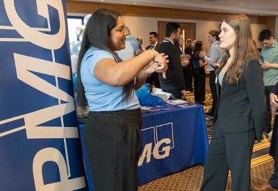 Recruiter and student talking beside a company booth display.