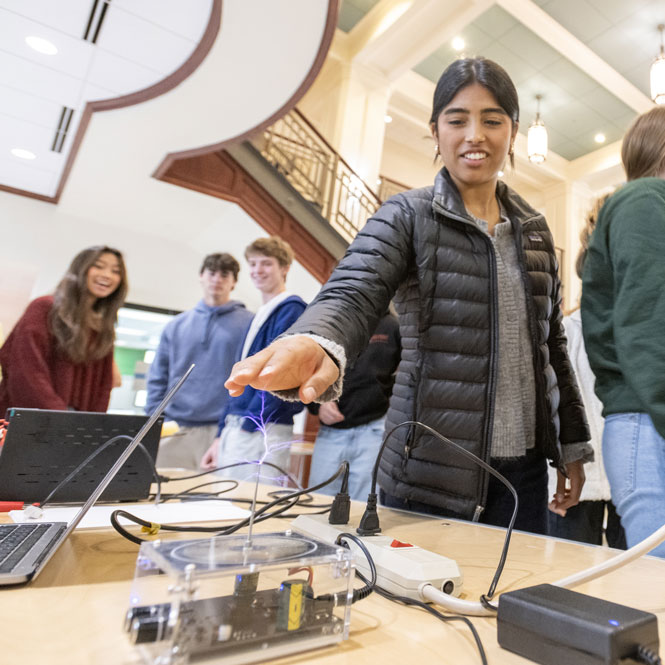 A student interacts with a static electricity demonstration device while classmates observe during a hands-on STEM activity.