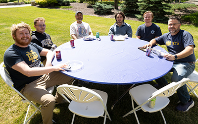 Staff members sit together outdoors, sharing a meal and conversation during the Staff Appreciation Lunch.