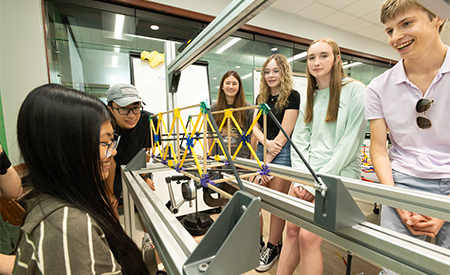 Students watch as a model bridge is tested in an engineering lab.