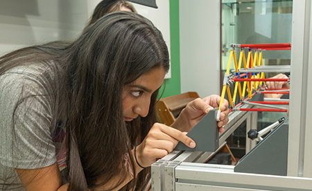 A student examines a model bridge during a structural engineering activity.