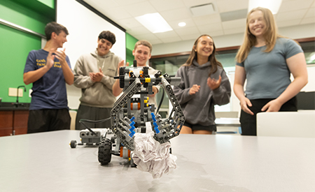 Students react as a robot completes a task during a robotics activity.