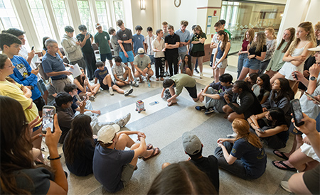 Students gather around a small robot during a hands-on engineering activity.