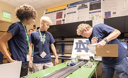 Students watch as an instructor demonstrates a slot car race on a model track.