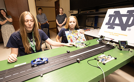Two students race slot cars on a model track during the electrical engineering summer camp.