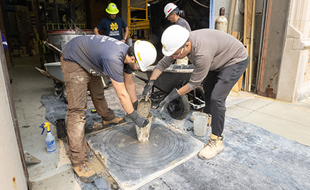 Two researchers work together to prepare freshly mixed concrete for casting outside the Structural Systems Laboratory.