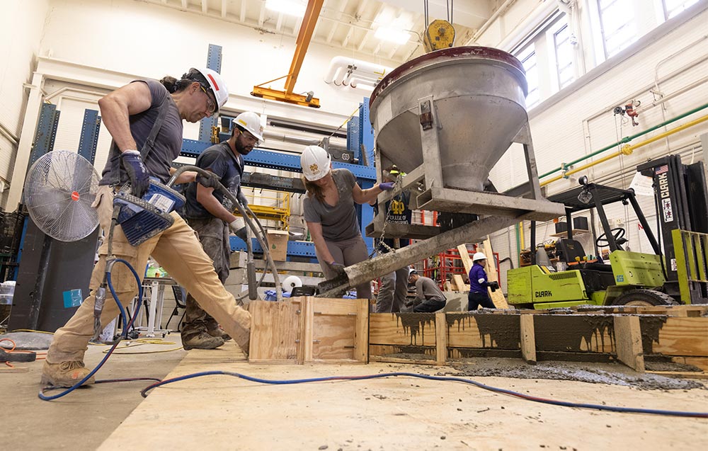Researchers pour concrete into a wooden form in the Structural Systems Laboratory.