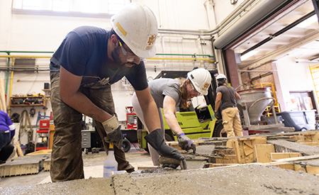 A researcher works with freshly poured concrete in a form during specimen casting.