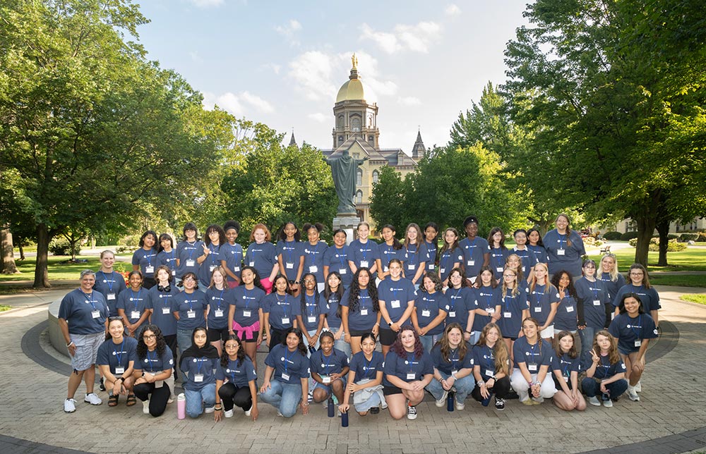 Students and instructors from the GE Aerospace Innovation & Discovery Camp pose for a group photo with the Main Building at Notre Dame in the background.